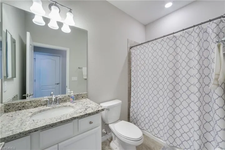 Bathroom featuring curtained shower, vanity, and toilet
