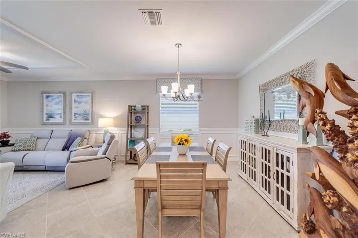 Dining area featuring a wainscoted wall, crown molding, and ceiling fan with notable chandelier