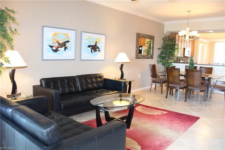 Living room featuring light tile patterned floors, crown molding, and a chandelier