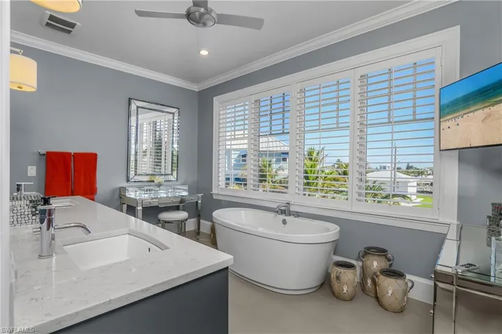 Full bathroom featuring double vanity, ornamental molding, a soaking tub, ceiling fan, and recessed lighting