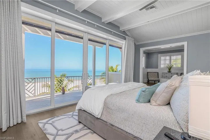 Bedroom featuring a water view, lofted ceiling with beams, access to outside, hardwood / wood-style flooring, and wooden ceiling