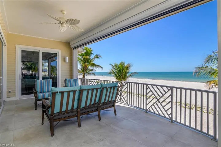 Balcony featuring ceiling fan and view of water and beach