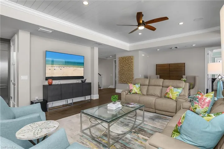 Living area featuring wood finished floors, ceiling fan, ornamental molding, and recessed lighting