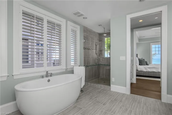 Full bath with connected bathroom, a stall shower, a freestanding bath, and recessed lighting