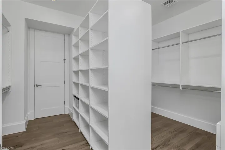 Walk in closet with dark wood finished floors