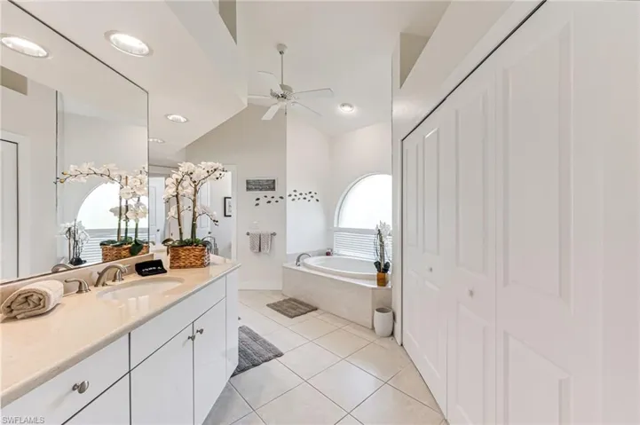Full bath featuring a bath, vanity, tile patterned flooring, and lofted ceiling