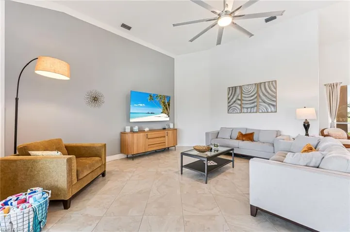 Living room featuring high vaulted ceiling, a ceiling fan, and light marble finish flooring