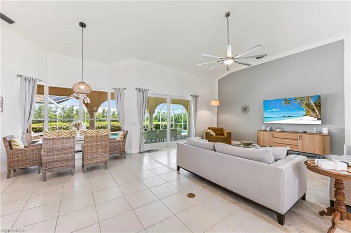 Living area featuring high vaulted ceiling, a ceiling fan, and light marble finish floors