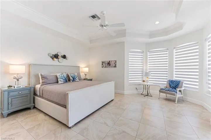 Bedroom featuring access to outside, a tray ceiling, a ceiling fan, light tile patterned flooring, and recessed lighting