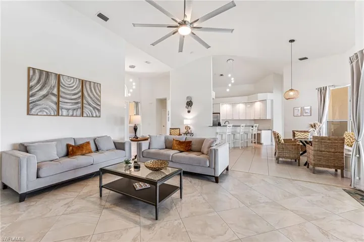 Living room with high vaulted ceiling, a ceiling fan, and light tile patterned flooring