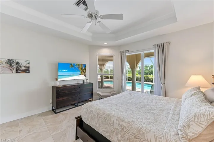 Bedroom with crown molding, a raised ceiling, recessed lighting, ceiling fan, and a closet