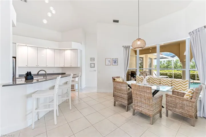 Kitchen with stainless steel fridge, dark countertops, a kitchen bar, high vaulted ceiling, and a peninsula