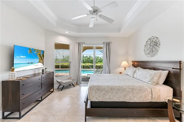 Tiled bedroom featuring access to outside, a raised ceiling, a ceiling fan, ornamental molding, and recessed lighting