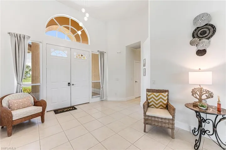 Living area featuring a ceiling fan, high vaulted ceiling, and light tile patterned floors