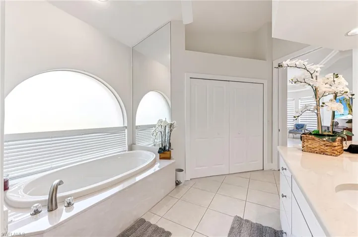 Bathroom featuring a bath, tile patterned flooring, vanity, and high vaulted ceiling