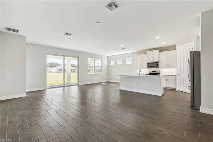 Unfurnished living room featuring sink and dark hardwood / wood-style flooring