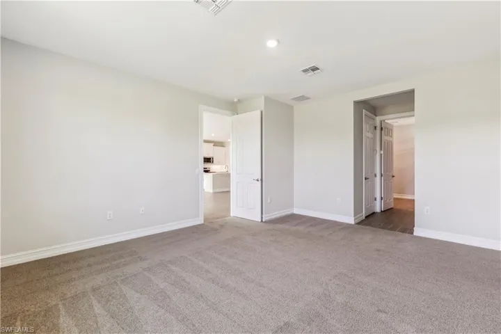 Unfurnished bedroom with ensuite bath and dark carpet