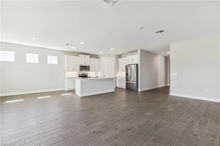 Unfurnished living room with sink and dark wood-type flooring