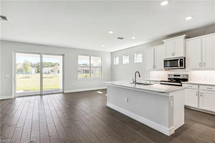 Kitchen featuring white cabinetry, a kitchen island with sink, appliances with stainless steel finishes, decorative backsplash, and sink