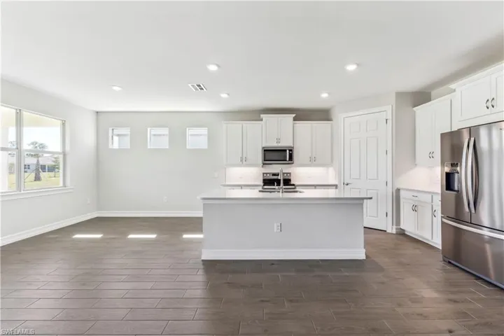 Kitchen featuring sink, stainless steel appliances, a kitchen island with sink, and white cabinetry