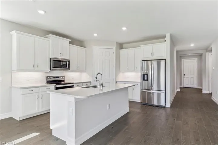 Kitchen featuring a center island with sink, stainless steel appliances, white cabinetry, and sink