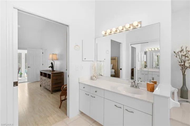 Ensuite bathroom featuring ensuite bathroom, a towering ceiling, tile patterned flooring, and vanity