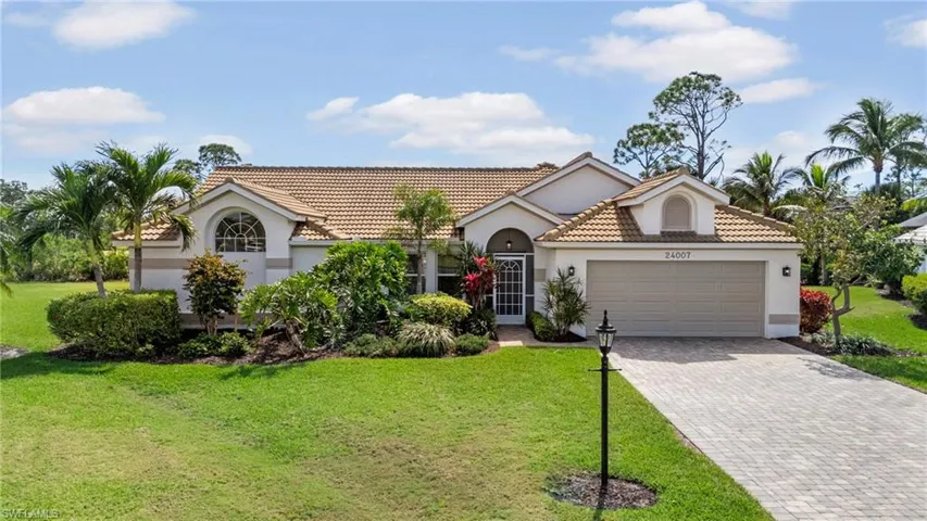 Mediterranean / spanish-style house featuring a tiled roof, an attached garage, decorative driveway, a front yard, and stucco siding