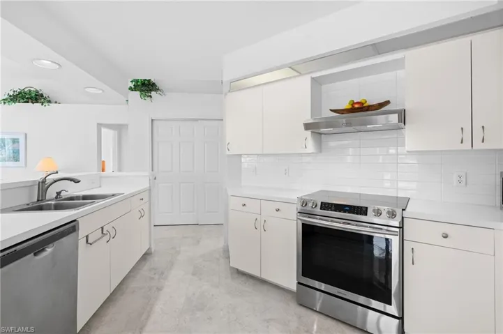 Kitchen featuring stainless steel appliances, tasteful backsplash, light countertops, a sink, and under cabinet range hood