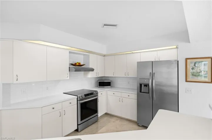 Kitchen featuring open shelves, stainless steel appliances, tasteful backsplash, light countertops, and exhaust hood