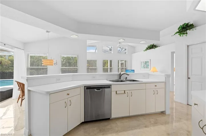 Kitchen featuring dishwasher, light countertops, a sink, and marble finish floor