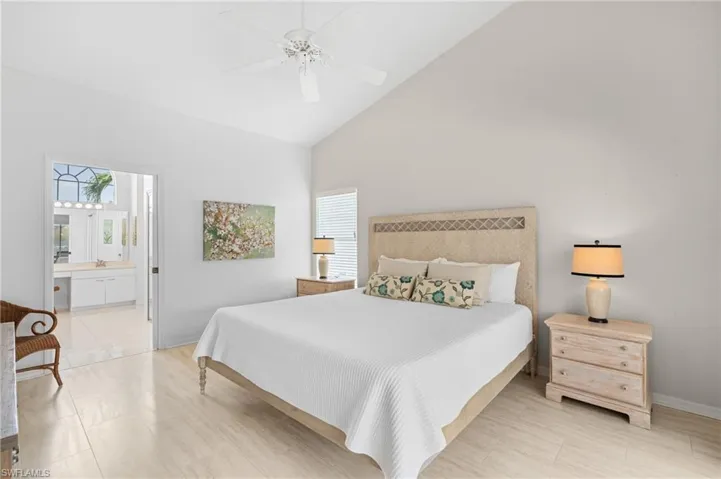 Bedroom with high vaulted ceiling, multiple windows, baseboards, and a ceiling fan