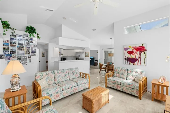 Living room with vaulted ceiling, visible vents, and a ceiling fan