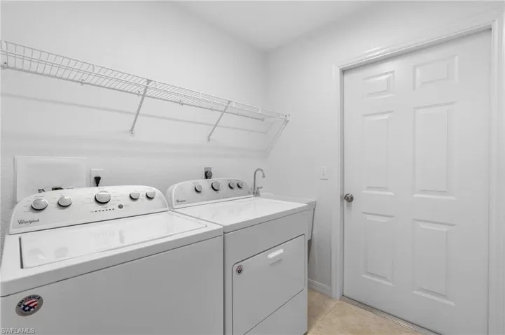Clothes washing area featuring laundry area, light tile patterned flooring, and washing machine and clothes dryer