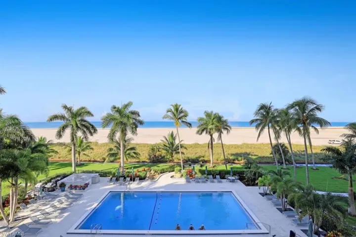 Community pool featuring a beach view, a patio area, and a water view