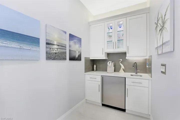 Bar featuring tasteful backsplash, a sink, fridge, indoor wet bar, and baseboards