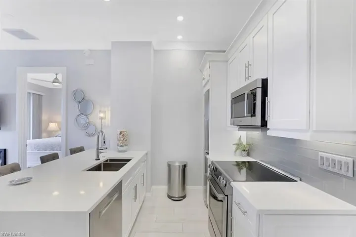 Kitchen featuring a peninsula, a sink, baseboards, light countertops, and appliances with stainless steel finishes