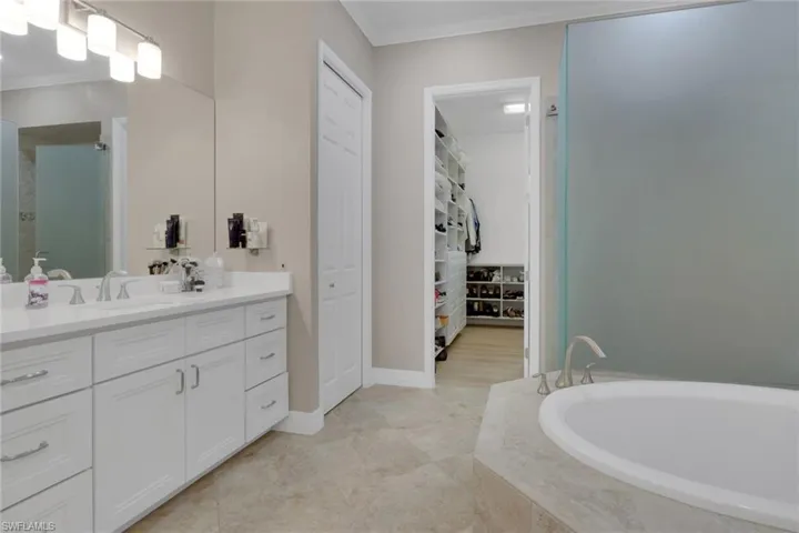 Full bath with ornamental molding, vanity, a spacious closet, and a bath
