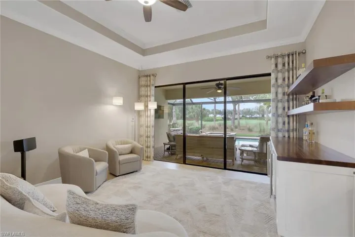 Living room featuring ceiling fan, a tray ceiling, and crown molding