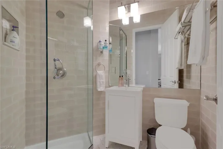 Bathroom featuring vanity, a shower stall, and tile walls
