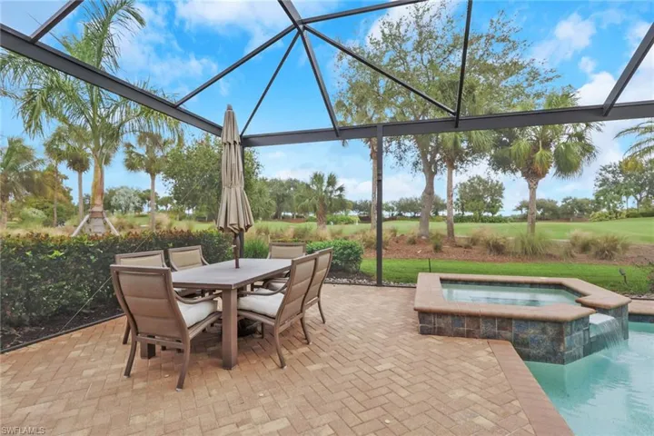 View of patio featuring outdoor dining area, glass enclosure, a pool with connected hot tub, and a sunroom