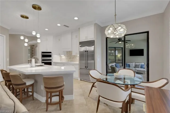 Kitchen with ornamental molding, appliances with stainless steel finishes, white cabinets, a breakfast bar area, and tasteful backsplash
