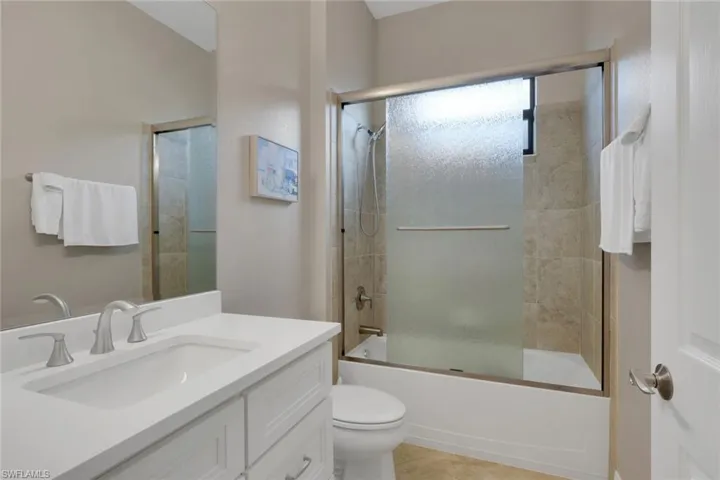 Bathroom featuring combined bath / shower with glass door, vanity, and light tile patterned flooring