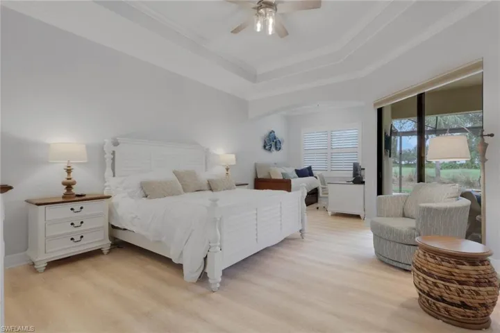 Bedroom featuring access to outside, light wood-style flooring, ceiling fan, crown molding, and a tray ceiling