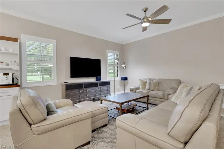 Living area with ornamental molding and a ceiling fan