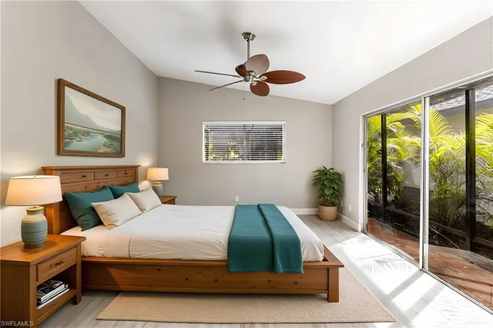Bedroom featuring vaulted ceiling, access to outside, a ceiling fan, and wood finished floors