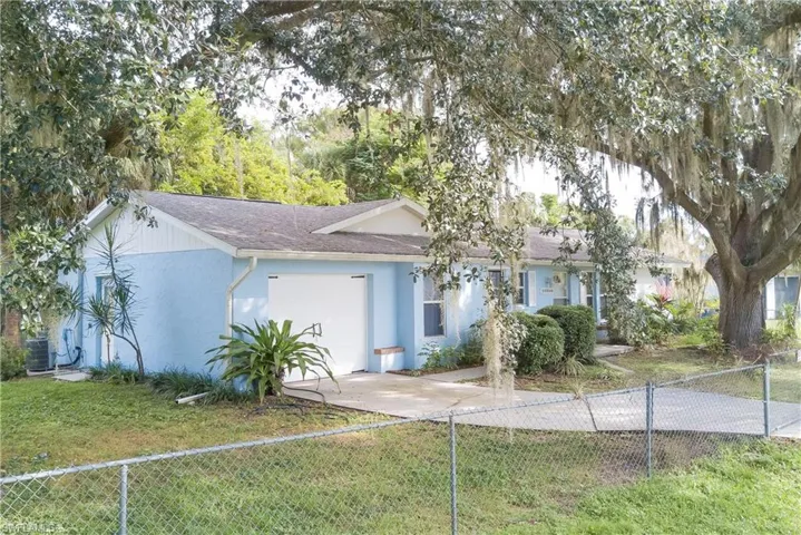 Single story home featuring a fenced front yard, a garage, driveway, roof with shingles, and stucco siding