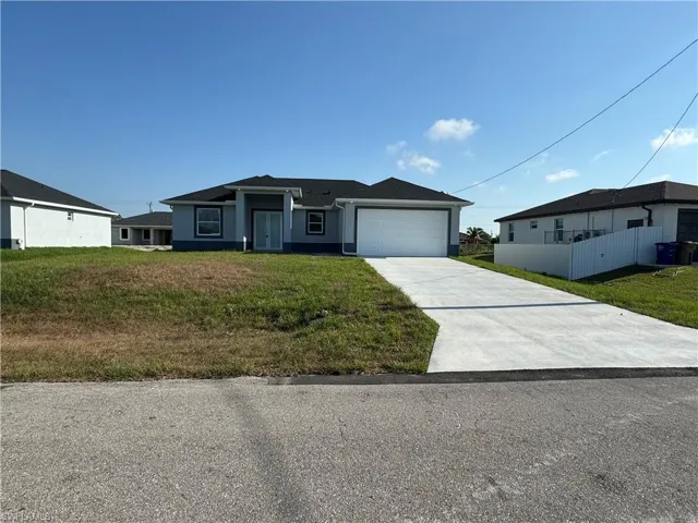 Ranch-style home featuring a garage and a front lawn