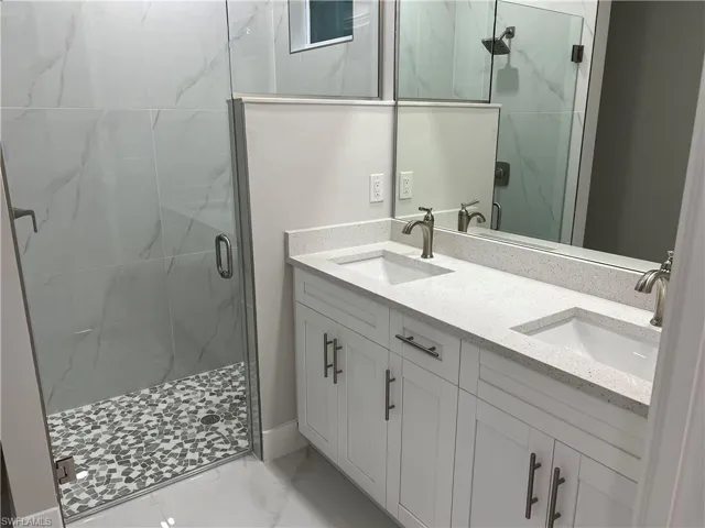 Bathroom with double vanity, walk in shower, and tile floors