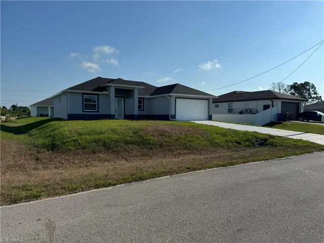 Ranch-style house with a garage and a front lawn