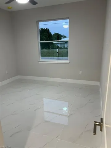 Tiled empty room featuring ceiling fan